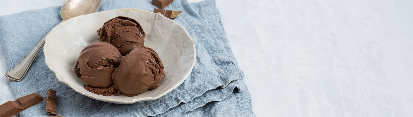 A picture of a bowl of chocolate ice cream, served on a table.